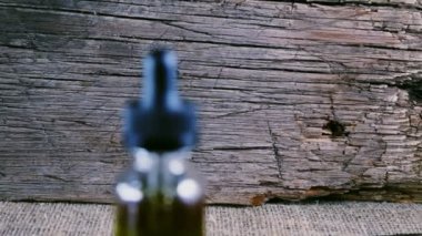 Bir şişe esrar konsantresi CBD, kurumuş marihuana tomurcukları ve tahta bir çuval kumaş arka planında kenevir yaprağının yanında duruyor. 4k