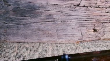 Bir şişe esrar konsantresi CBD, kurumuş marihuana tomurcukları ve tahta bir çuval kumaş arka planında kenevir yaprağının yanında duruyor. 4k