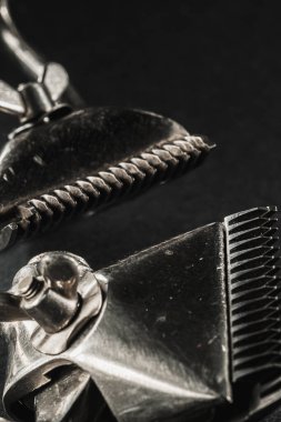 Siyah bir yüzeyde eski berber aletleri vardır. İki adet eski el yapımı saç makasıdır. siyah monokrom. Yakın plan. Berber dükkanı geçmişi. farklı gölgeler. düşey yönelim
