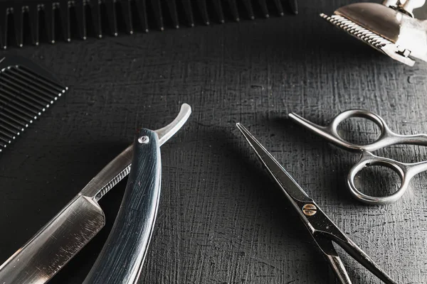 vintage barber tools. dangerous razor, hairdressing scissors, old manual clipper, combs, shaving brush. black monochrome. black background.