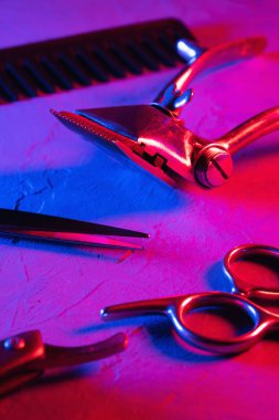 Kırmızı ve mavi psikedelik sinematik estetik. Yüzeyde eski berber aletleri var. Klasik manuel saç makasi ustura kuaför makasi. Dikey yönelim