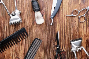 Yıpranmış ahşap bir yüzeyde eski berber aletleri vardır. Klasik manuel saç makası, tarak, jilet, kuaför makası. Üst manzara, düz yatış. Berber dükkanı geçmişi. yatay yönelim.