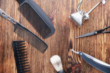 Yıpranmış ahşap bir yüzeyde eski berber aletleri vardır. Klasik manuel saç makası, tarak, jilet, kuaför makası. Üst manzara, düz yatış. Berber dükkanı geçmişi. yatay yönelim.