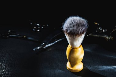 Koyu arkaplanda tıraş fırçası, kuaför aletleri, makas, manuel saç makası.