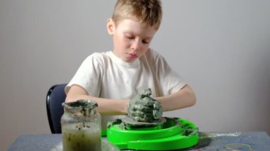 Yedi yaşında, kille kirlenmiş bir çocuk çömlekçi çarkında kilden bir ürün yapmaya konsantre oluyor. Uzun ya da geniş açı. 4 bin. Yatay