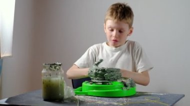 Yedi yaşında, kille kirlenmiş bir çocuk çömlekçi çarkında kilden bir ürün yapmaya konsantre oluyor. Uzun ya da geniş açı. 4 bin. Yatay