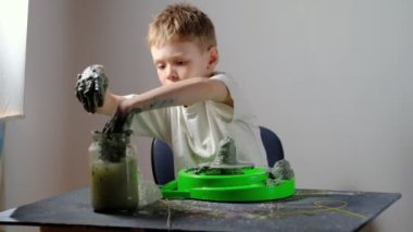 Yedi yaşında, kille kirlenmiş bir çocuk çömlekçi çarkında kilden bir ürün yapmaya konsantre oluyor. Uzun ya da geniş açı. 4 bin. Yatay