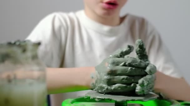 一个被黏土弄脏了的7岁男孩正专注于在陶工的轮子上制作一种黏土产品 — 图库视频影像