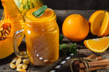 Nane yapraklı balkabağı püresi, bir parça çiğ balkabağı ve portakallı kavanozda ahşap arka planda nane yaprağı. yatay yönelim.