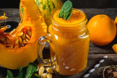 Nane yapraklı balkabağı püresi, bir parça çiğ balkabağı ve portakallı kavanozda ahşap arka planda nane yaprağı. yatay yönelim.