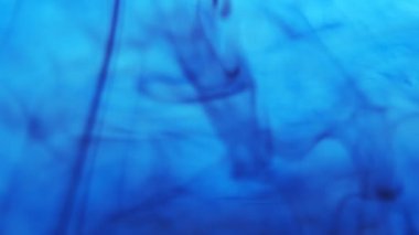 Siyah mürekkep yayılır ve mavi suyun altında kıvrılır.