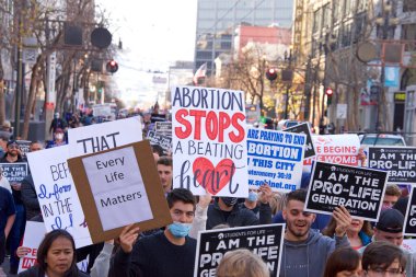 San Francisco, CA - 23 Ocak 2021: 17. Yaşam Yürüyüşü 'nün tanımlanamayan katılımcıları ellerinde yaşam işareti ve pankartlarıyla Market Caddesi' nde yürüyor. Bazı insanlar maske takıyor, bazıları takmıyor..