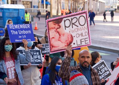 San Francisco, CA - 23 Ocak 2021: 17. Yaşam Yürüyüşü 'nün tanımlanamayan katılımcıları ellerinde yaşam işareti ve pankartlarıyla Market Caddesi' nde yürüyor. Bazı insanlar maske takıyor, bazıları takmıyor..