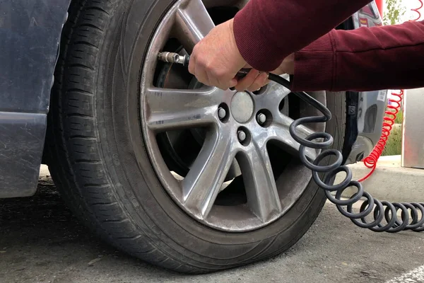 Close up of an older woman, female hands using automated air pump to inflate car tire with low pressure.