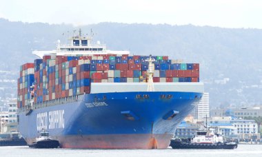 Oakland, CA - Apr 3, 2021: Multiple tugboats work in tandem to assist cargo ship COSCO EUROPE to turn prior to docking at the Port of Oakland.