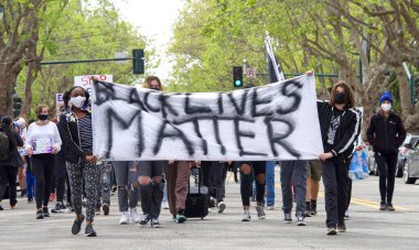 Alameda, CA - 24 Nisan 2021: Washington Park 'tan Alameda Polis Karakolu' na yürüyüş için yürümekte olan gençlik lider Polis Vahşeti Yürüyüşü 'nde tabela tutan kimliği belirsiz katılımcılar.