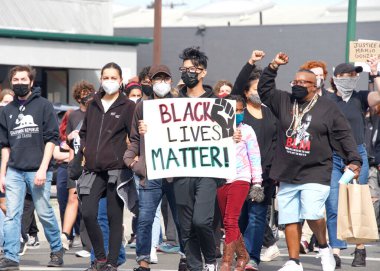 Alameda, CA - 24 Nisan 2021: Washington Park 'tan Alameda Polis Karakolu' na yürüyüş için yürümekte olan gençlik lider Polis Vahşeti Yürüyüşü 'nde tabela tutan kimliği belirsiz katılımcılar.