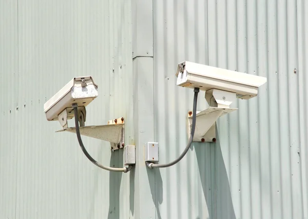 Security cameras on the corner of an industrial building. Hard wired into the building.