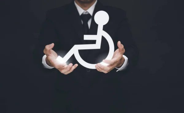 Biznesmen Trzymający Białą Ikonę Wózka Inwalidzkiego Czarnym Tle Pomaganie Osobom — Zdjęcie stockowe