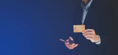 İş adamı kredi kartı tutuyor ve cep telefonu kullanıyor. Çevrimiçi alışveriş kavramı, bankacılık ve çevrimiçi alışveriş. Kapatın..