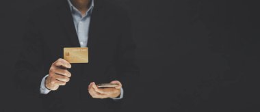 İş adamı kredi kartı tutuyor ve cep telefonu kullanıyor. Çevrimiçi alışveriş kavramı, bankacılık ve çevrimiçi alışveriş. Kapatın..