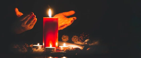Woman Praying and worship to GOD Using hands to pray in religious beliefs and worship christian with Red Candle with fire against defocused lights in darkness with in the dark Background