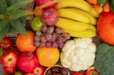 Sebzeler, elmalar, üzümler, portakallar ve muz ahşap sepette havuç, domates, guava, biber, patlıcan ve salata. Sağlıklı gıda kavramı.