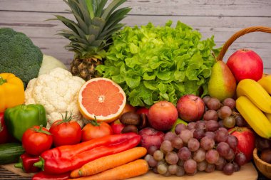 Sebzeler, elmalar, üzümler, portakallar ve muz ahşap sepette havuç, domates, guava, biber, patlıcan ve salata. Sağlıklı gıda kavramı.