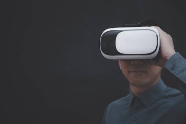 Sanal gerçeklik gözlüğü takan işadamı VR ve grafik ekranında karanlık arkaplan, Teknoloji Süreç Sistemi İş dünyası, başarı ve takım çalışması kavramı üzerine bir medya ekranının dokunuşunu inceliyor