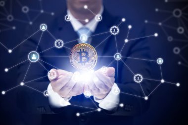 İş adamı mavi arka planda bir iş ağının parçası olarak bir bitcoin tutuyor. Bitcoin kripto para birimi fikirleri kavramı ve sanal finansal şema, yeni sanal para biriminin dijital sembolü