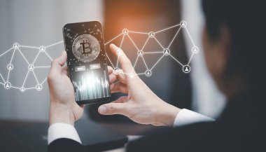 Bitcoin konsepti yığınları arasında ekran başında Bitcoin grafiği olan akıllı telefon. İş adamı büyük BUY ve SELL düğmeleri ile mobil uygulama ekranına dokunuyor. Borsada Bitcoin, Kripto para ve finans.