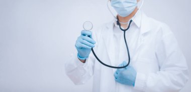 Steteskop takan doktor ya da bilim adamı. Tıbbi maske ve eldivenler takan, neşeli, olgun doktor kameraya, sağlık hizmetine ve tıbba poz veriyor ve gülümsüyor..