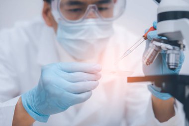 Koronavirüs için mikroskopla çalışan biyokimya araştırmacısı, bilim, kimya, biyoloji, tıp ve insan kavramı için kimyasal sıvı içeren laboratuvar camları. 