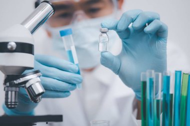 Üniformalı bir yüz maskesi takan doktor ya da bilim adamının üzerinde COVID-19 aşısı, sağlık sigortası ve tıbbi konsept var. .