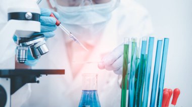 Koronavirüs için mikroskopla çalışan biyokimya araştırmacısı, bilim, kimya, biyoloji, tıp ve insan kavramı için kimyasal sıvı içeren laboratuvar camları. 