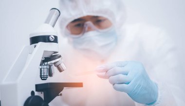 Koronavirüs için mikroskopla çalışan biyokimya araştırmacısı, bilim, kimya, biyoloji, tıp ve insan kavramı için kimyasal sıvı içeren laboratuvar camları. 