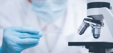 Koronavirüs için mikroskopla çalışan biyokimya araştırmacısı, bilim, kimya, biyoloji, tıp ve insan kavramı için kimyasal sıvı içeren laboratuvar camları. 