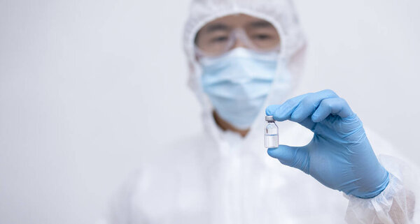 Крупный человек врач или ученый в форме носить маску для лица со стетоскопом держа COVID-19 вакцины, здравоохранения и медицинской концепции, вакцины Концепция борьбы с вирусом ковид-19 короны