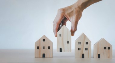 Ahşap masadaki mankenden, emlak almayı planlayan, emlak almayı ve en iyisini seçmeyi planlayan el yapımı ahşap ev modeli. Evden çalış ve ev konseptinde kal..