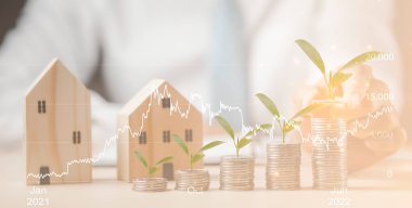 Para yığını ve yaprak ve çizgi işi Mini ahşap ev modeliyle ahşap masa üzerinde bağlantı, Emlak almayı planlama, emlak satın almak ve en iyisini seçmek, para tasarrufu 