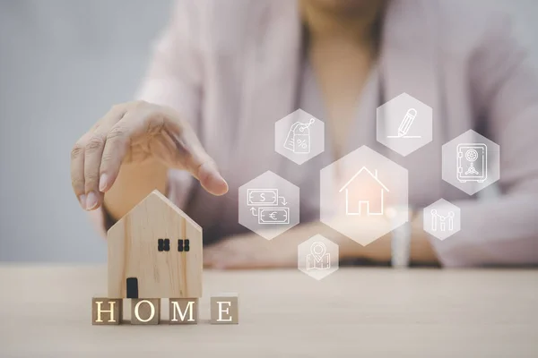 Home insurance and security ideas concept, Woman hand touch wooden home and icon of property value diagram, Business marketing and investment, Symbol of construction, security home concept
