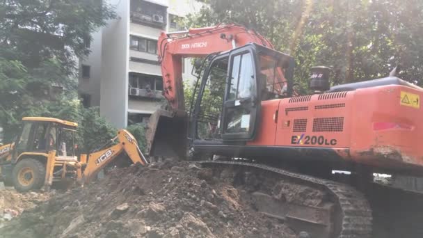 Red caterpillar driven hydraulic excavator and Yellow Jcbb  at work Lokgram Kalyan — Stock Video