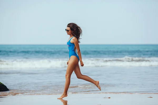 Uma mulher em fuga. Corredor feminino correndo durante o treino ao ar livre na praia. Bonito ajuste misto raça modelo Fitness ao ar livre . — Fotografia de Stock