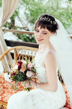 Portre, güzel mutlu gelin oturup açık havada kanepede.