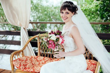 Portre, güzel mutlu gelin oturup açık havada kanepede.