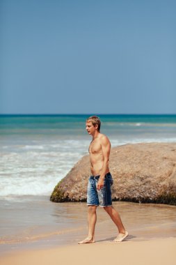 tropik sahilde yürüyen yakışıklı adam