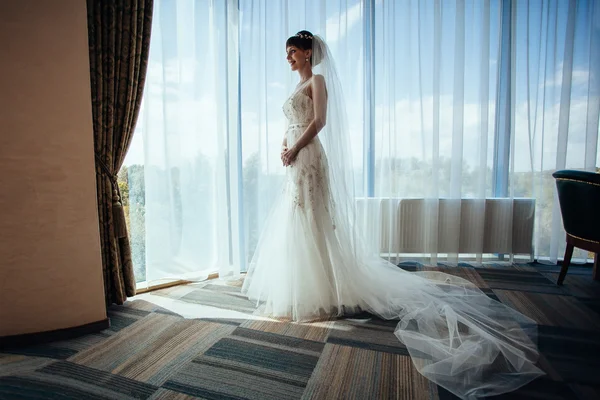 Portrait of the beautiful bride against a window indoors — Stock Photo, Image