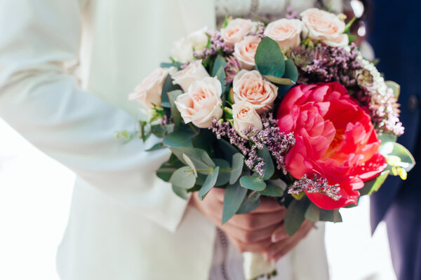 Bride holding wedding bouquet. Beautiful bouquet of roses and pe