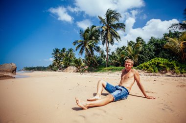 Adam bir tropikal plaj rahatlatıcı. Genç adam sunbat alarak tabaklanmış