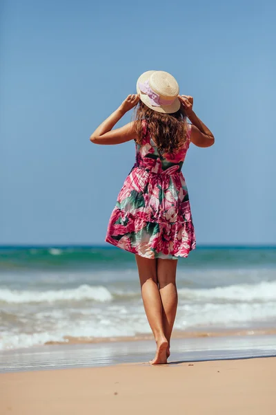 Retrato completo de Jovem mulher de pé em uma praia segurando — Fotografia de Stock